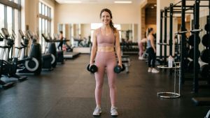 Woman holding dumbbells in gym — beginner strength training guide for women