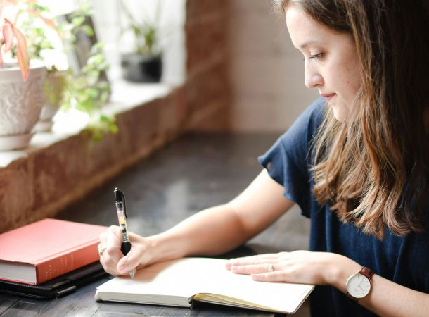 Woman journaling by a sunny window as part of emotional resilience practice