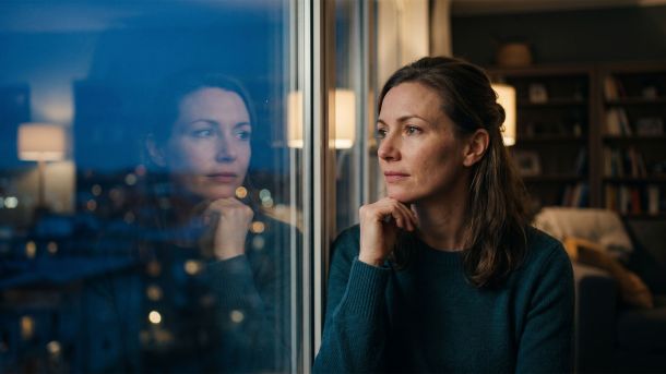 Woman sitting alone looking out a window in quiet reflection
