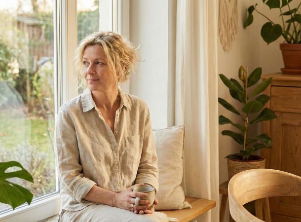 Eine Frau praktiziert achtsames Atmen in einem hellen, friedlichen Raum zur Stressreduktion.