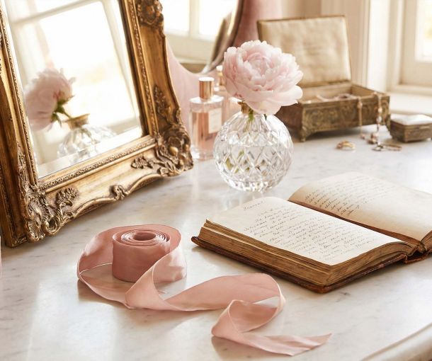 A sophisticated feminine vanity featuring a gold mirror and journal, representing the history of women's private education and health.